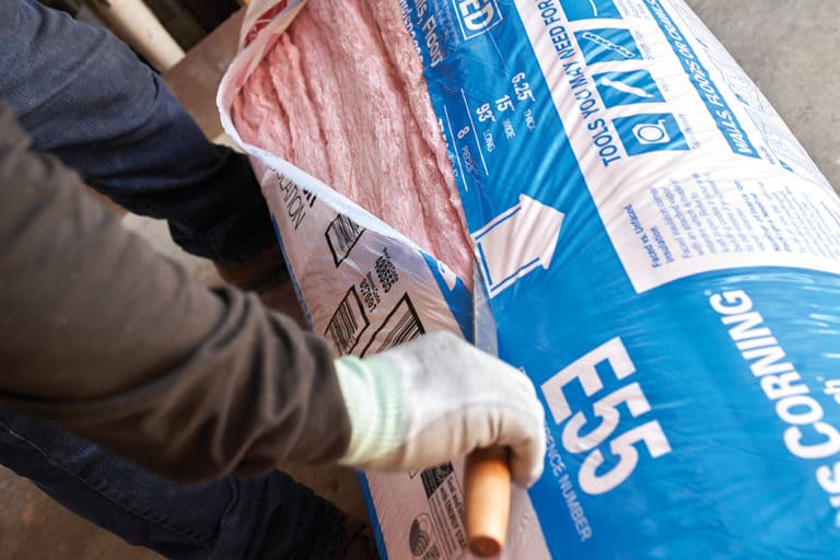 A worker opens a package of Owens Corning batt insulation