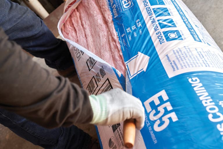 A worker opens a package of Owens Corning pink fiberglass batt insulation