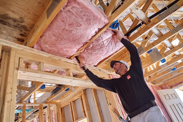 A worker installing pink insulation