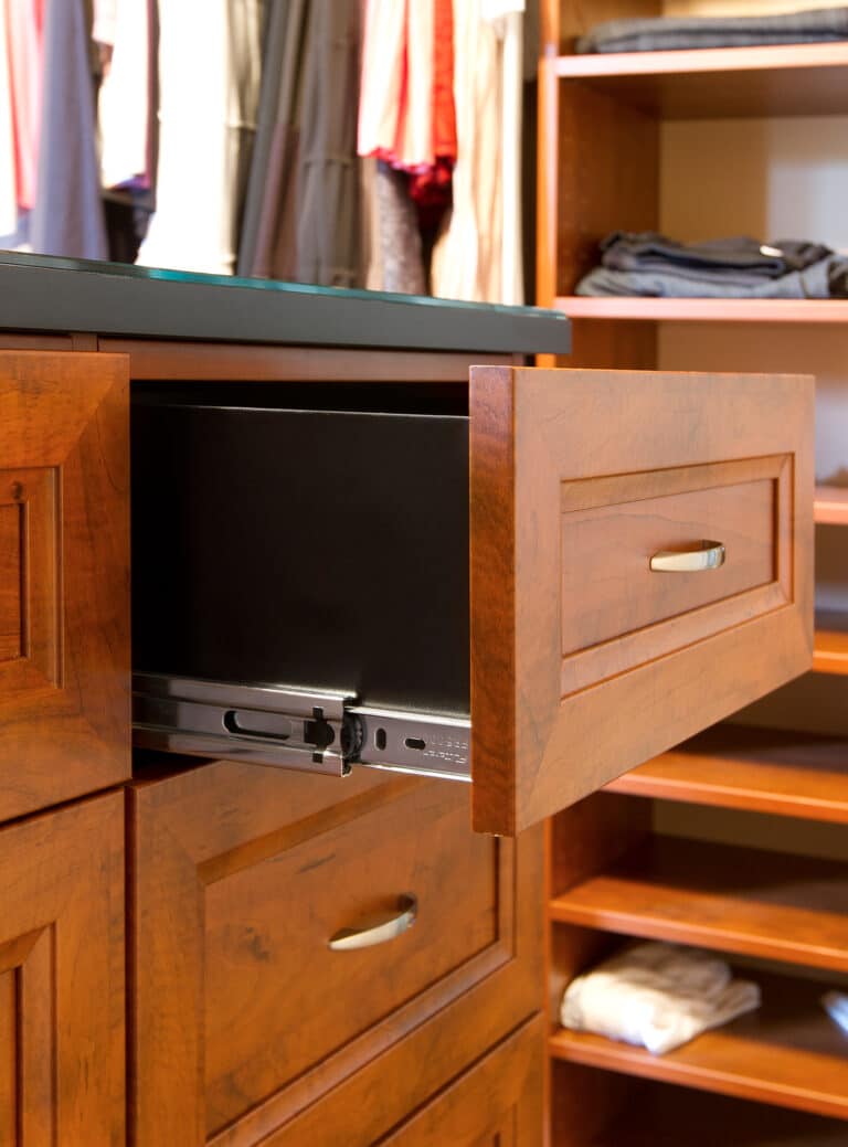 A master closet build out inside of a modern home with one of the drawers pulled open to show the custom closure system