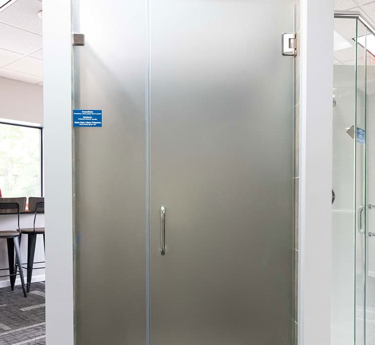 A frameless heavy glass door and panel with a stainless steel handle