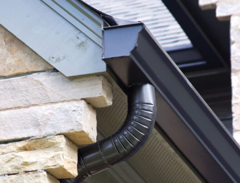 A black K-spout gutter installed on the side of a home