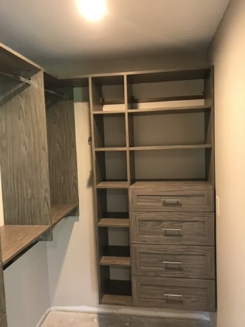Shelving and drawers with custom pulls inside of a custom closet design