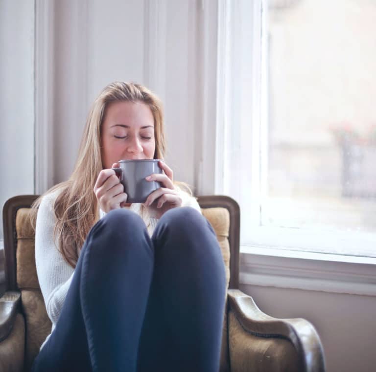 A woman sipping coffee inside of a home