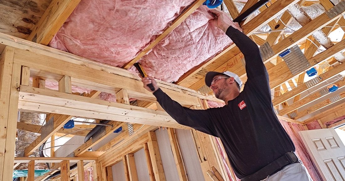 An installer putting up new Rockwool insulation in a home