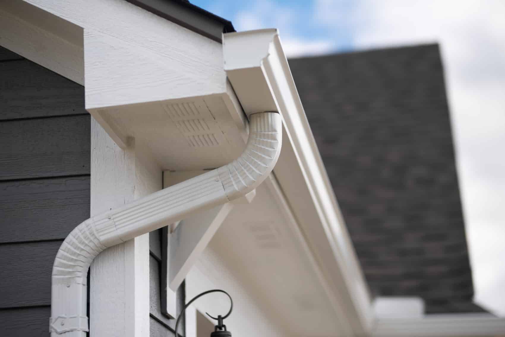 White gutters at the corner of a home's roof.