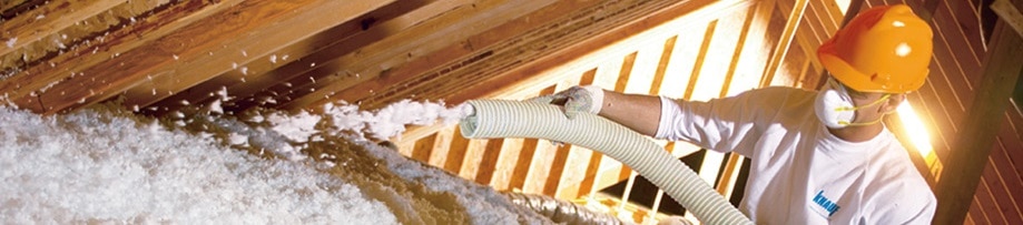 Attic insulation being blown in by a technician.